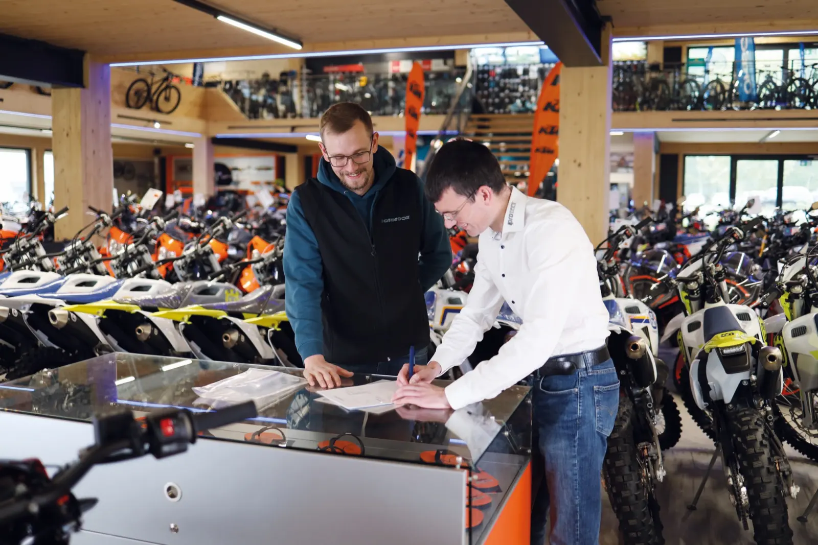 Motorradhändler und Berater unterschreiben an der Verkaufstheke einen Vertrag