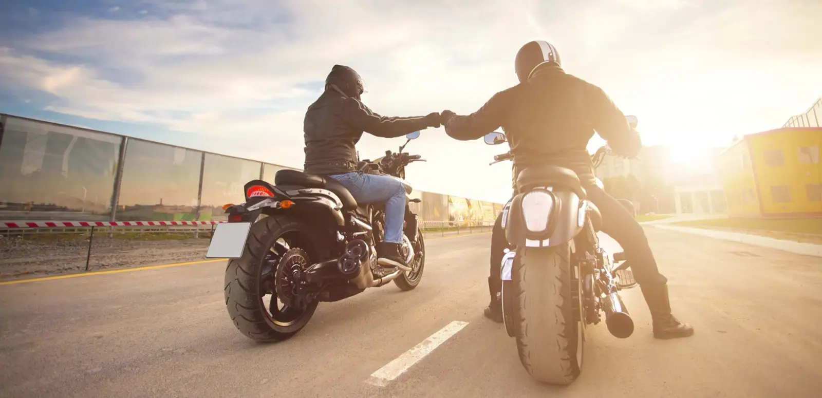 Zwei Motorradfahrer begrüßen sich bei Sonnenuntergang