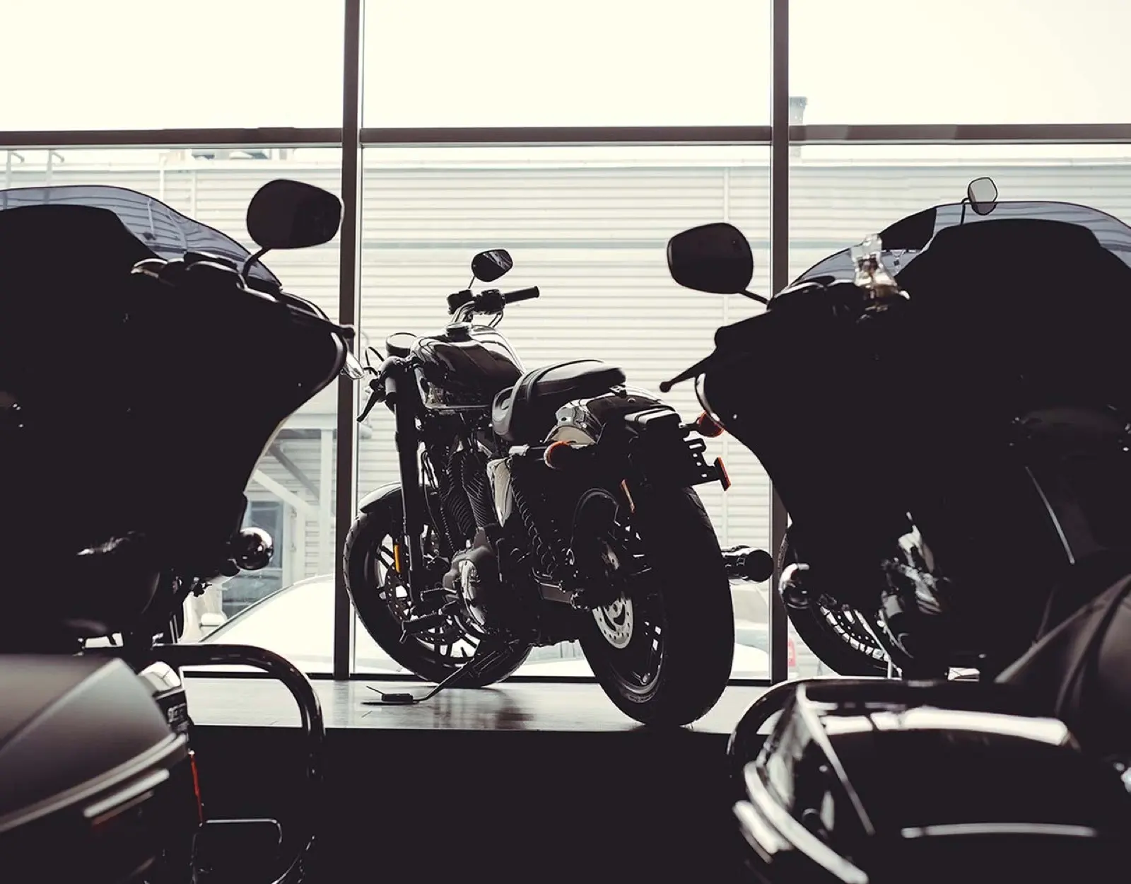 Motorräder als Silhouetten vor der Fensterfront eines Autohauses
